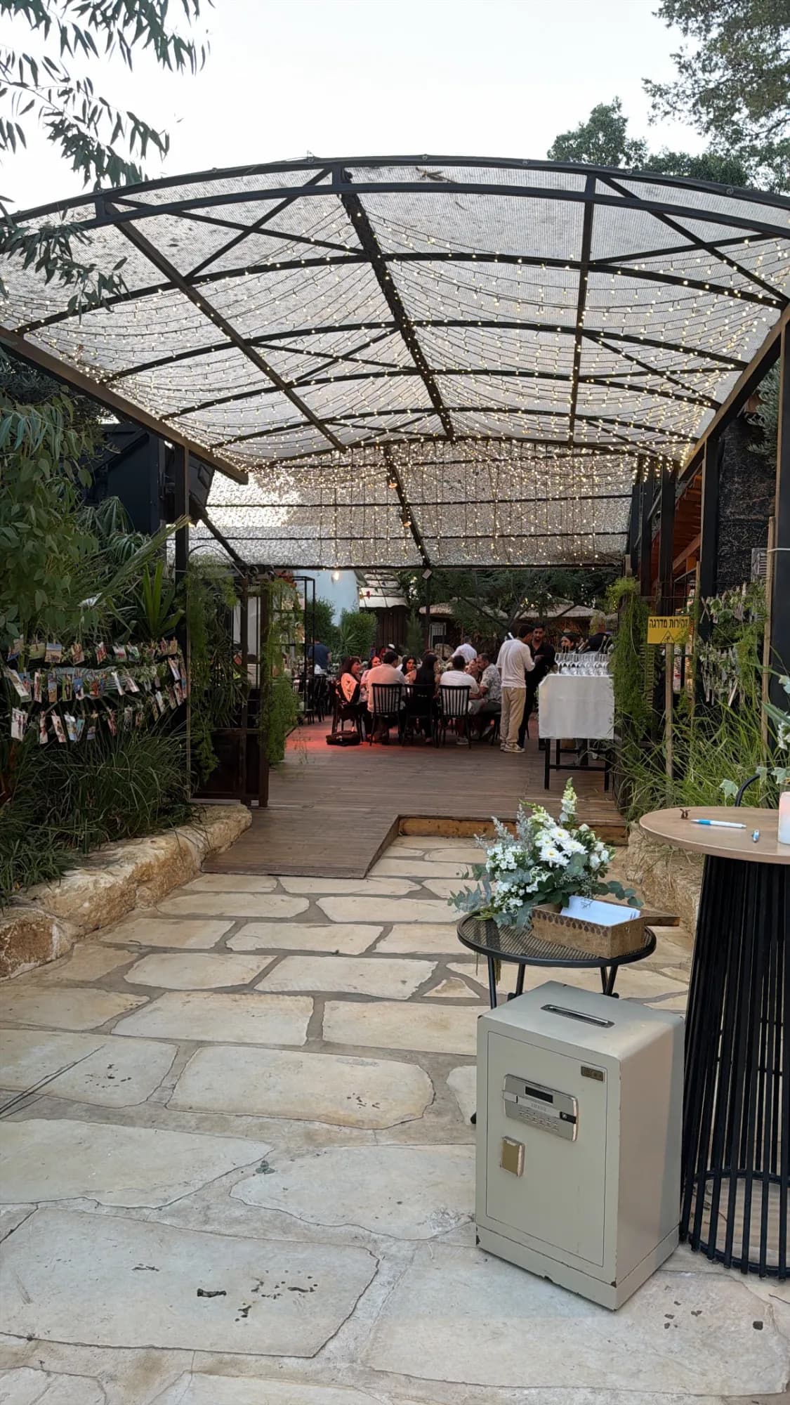 שביל הכניסה המרוצף מתחת לקירוי מקושת וצמחייה