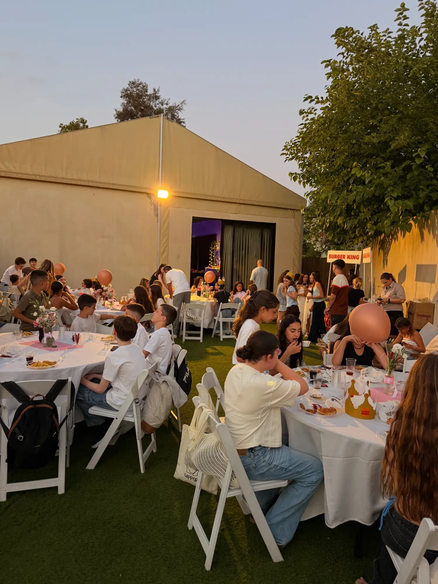 שולחנות אירוח בחצר על המדשאה לצד מבנה האירועים